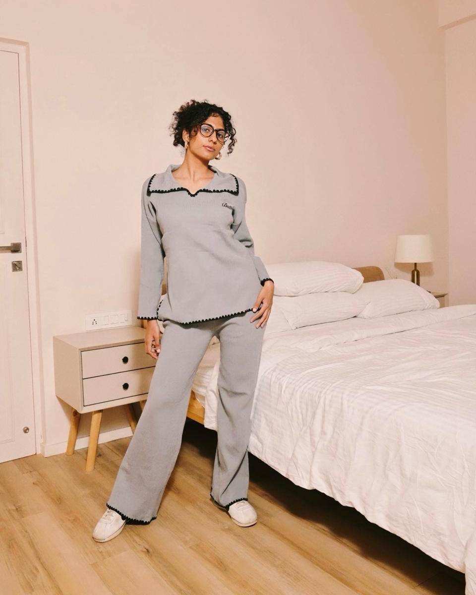 Person wearing a gray pajama set standing in a bedroom.
