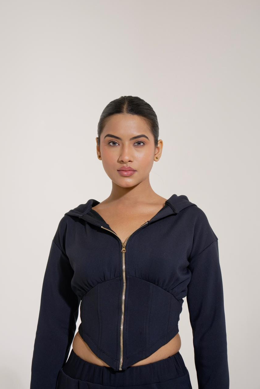 Woman wearing a navy blue zip-up hoodie against a plain background