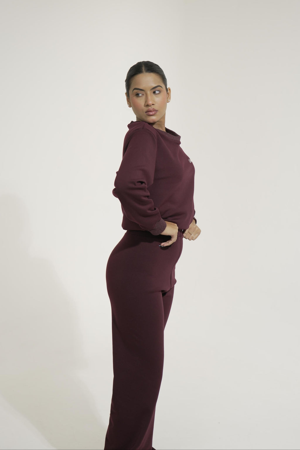 Woman wearing a maroon outfit against a white background
