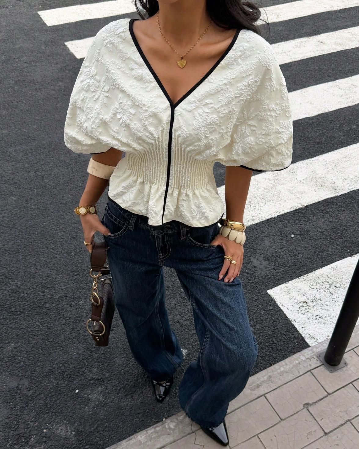 Person wearing a white textured top and blue jeans on a crosswalk