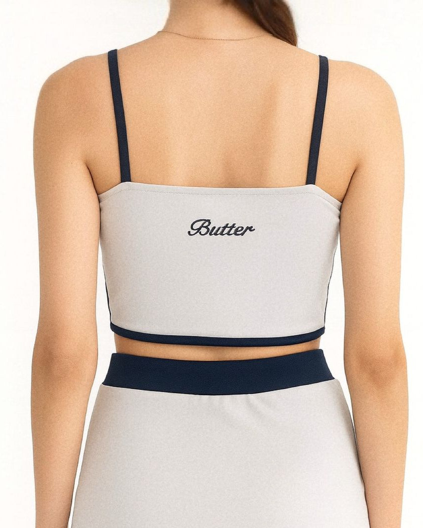 Person wearing a gray and navy two-piece swimsuit with 'Butter' branding on a white background